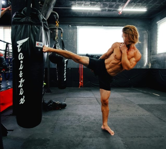 A man doing a kickbox kick in a gym