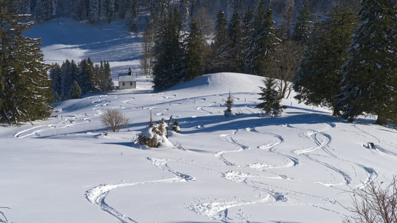 A snow covered hill with a ski lift in the distance