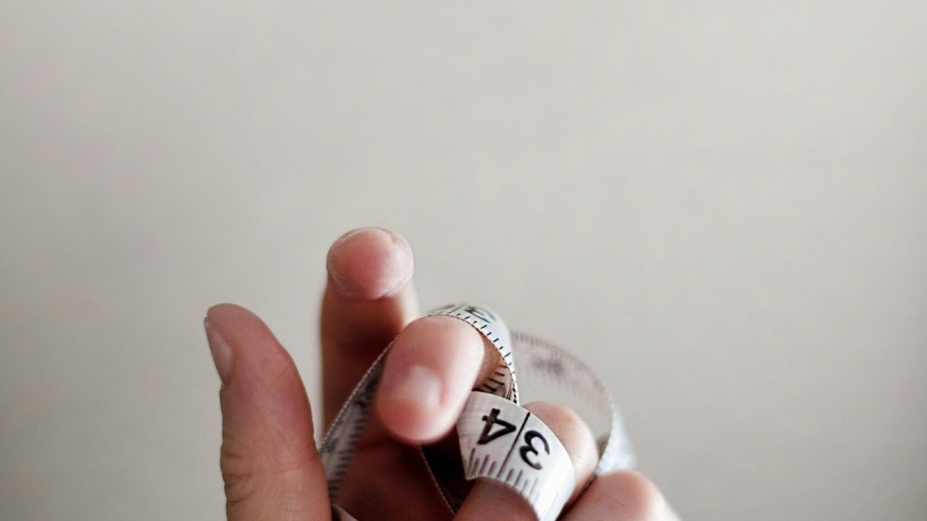 person's left hand wrapped by tape measure