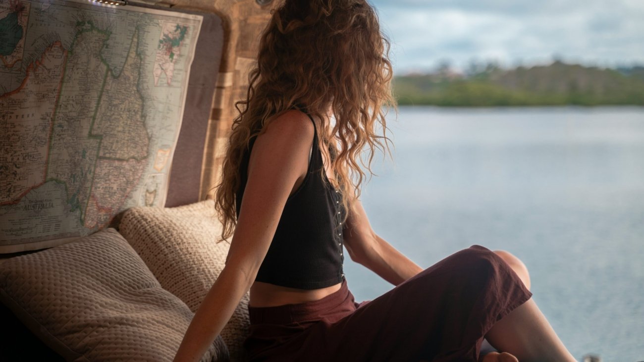 woman wearing black spaghetti strap top sitting viewing body of water